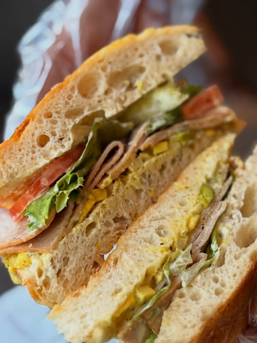 A close view of a club sandwich on ciabatta with turkey, lettuce, tomato and pickle