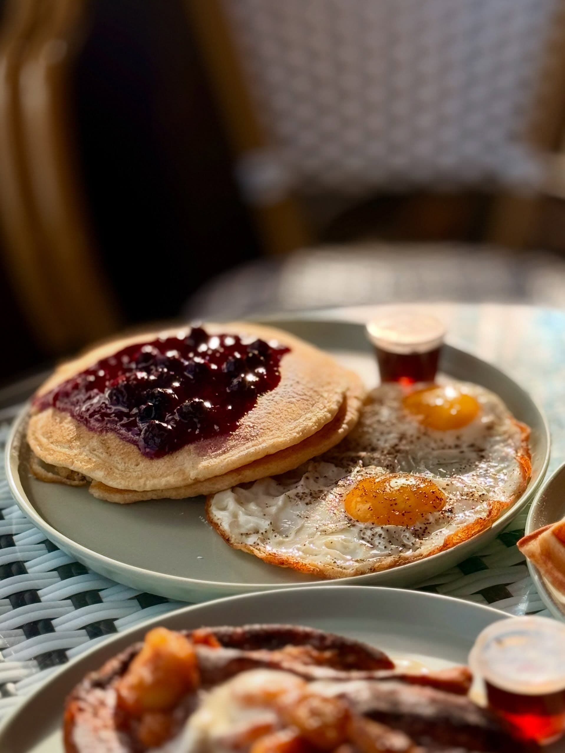 Stack of pancakes with eggs and breakfast sides