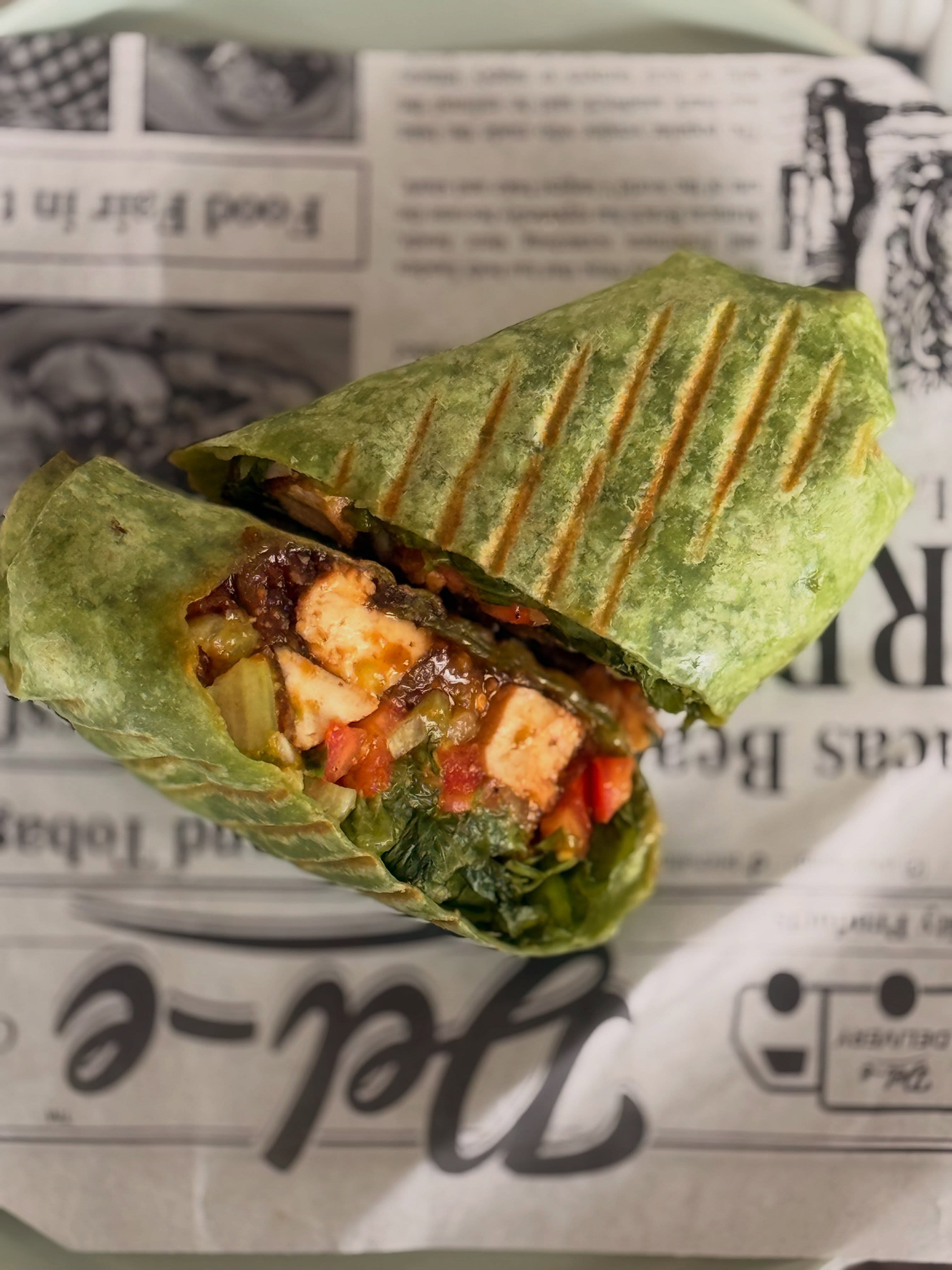 Teriyaki tofu spinach wrap cut open to show its filling